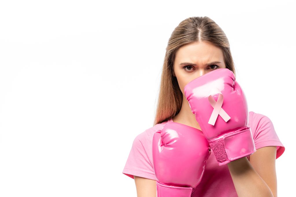 Νεαρή γυναίκα σε γάντια πυγμαχίας με ροζ κορδέλα κοιτάζοντας κάμερα που απομονώνεται σε λευκό - Φωτογραφία, εικόνα