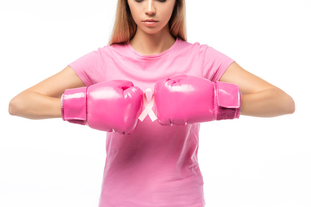 Widok upraw młodej kobiety w różowych rękawiczkach bokserskich trzymającej wstążkę świadomości raka piersi izolowanej na białym - Zdjęcie, obraz