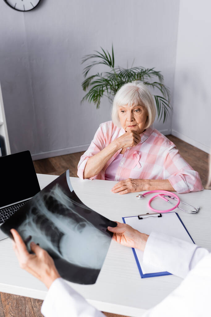 Επιλεκτική εστίαση της σκεπτικής ηλικιωμένη γυναίκα κάθεται και κοιτάζοντας ακτινογραφία θώρακος  - Φωτογραφία, εικόνα