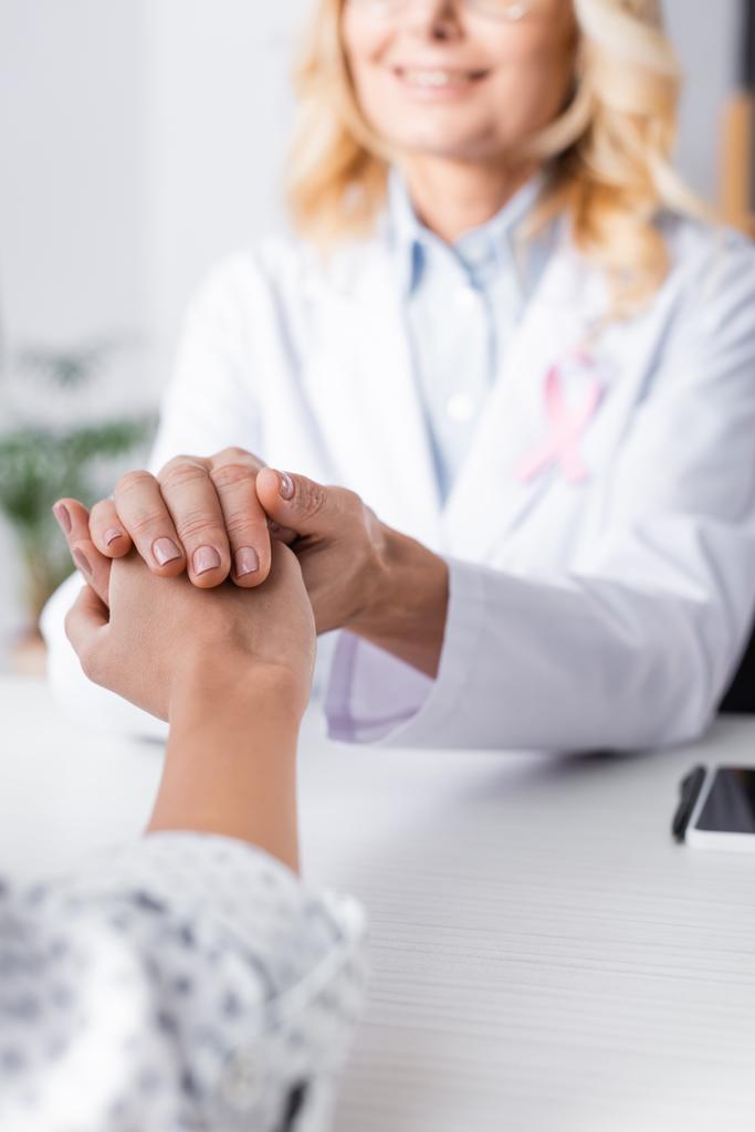 Concentration sélective du patient tenant la main avec le médecin en manteau blanc  - Photo, image