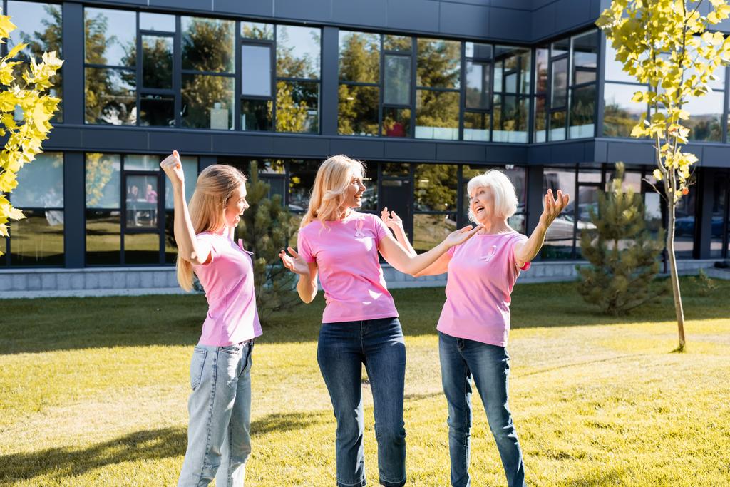 Aufgeregte Frauen in rosa T-Shirts mit Brustkrebsbändern - Foto, Bild