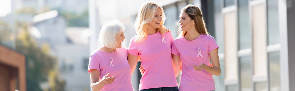 Panoramic shot of women with pink ribbons of breast cancer awareness outdoors - Photo, Image