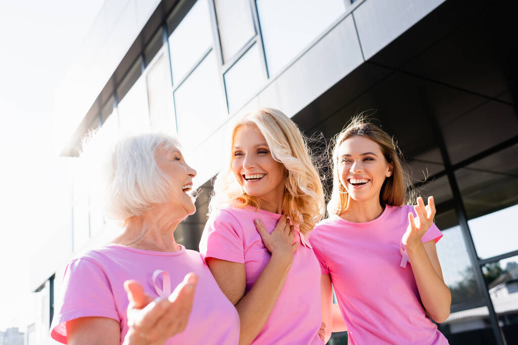 Donne in t-shirt rosa che ridono e si abbracciano all'aperto, concetto di cancro al seno - Foto, immagini