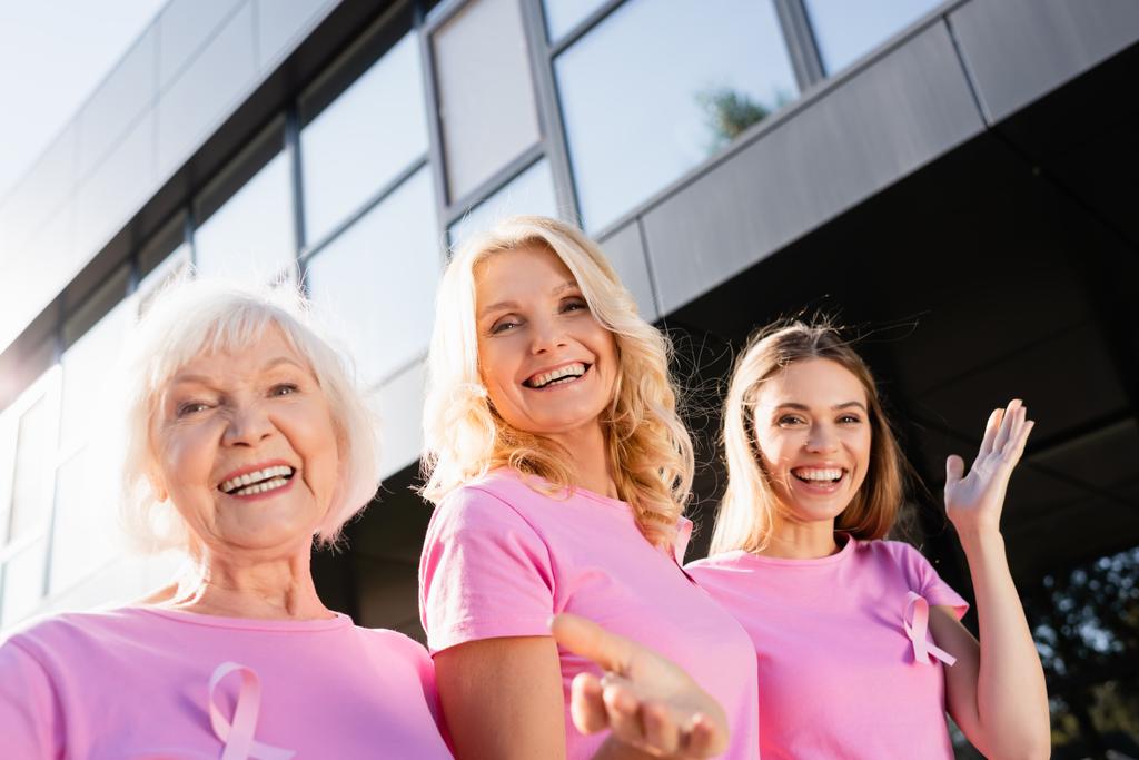 Femmes avec des signes de sensibilisation au cancer du sein étreignant et regardant la caméra - Photo, image