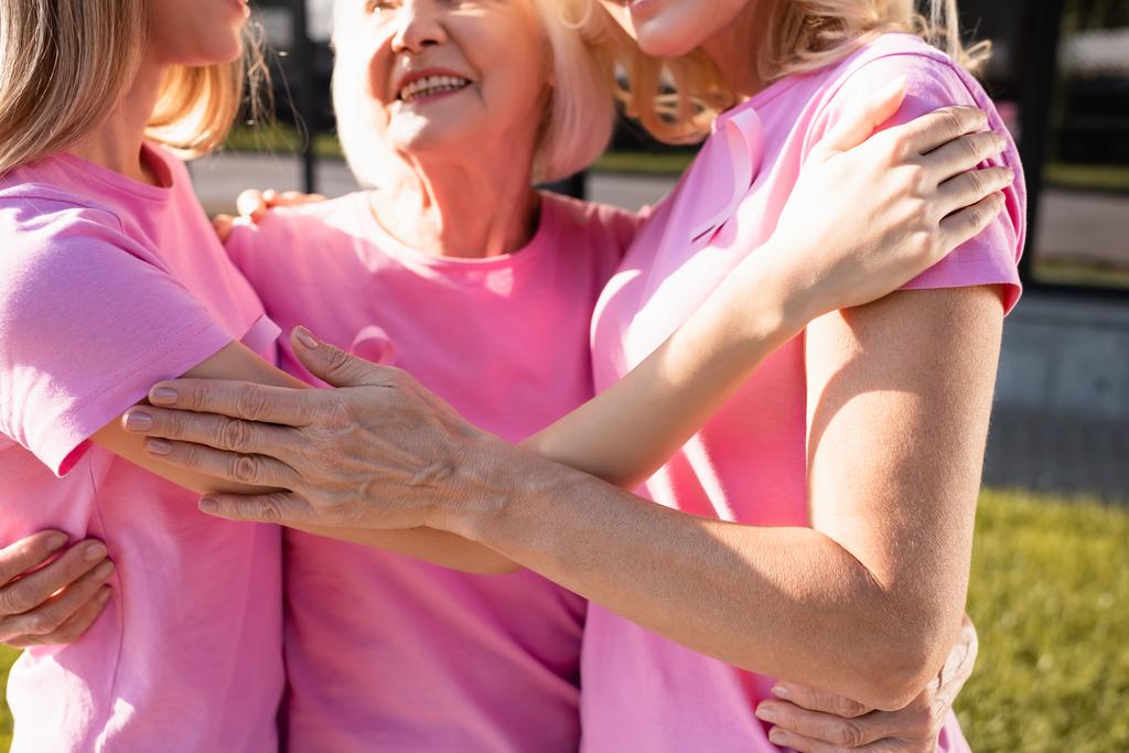 Vista recortada de tres mujeres en camisetas rosas abrazando, concepto de cáncer de mama - Foto, Imagen