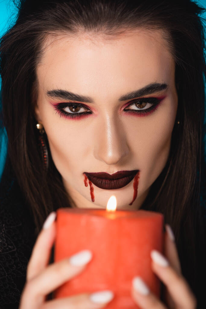 επιλεκτική εστίαση της γυναίκας με αίμα στο πρόσωπο κρατώντας αναμμένο κερί - Φωτογραφία, εικόνα