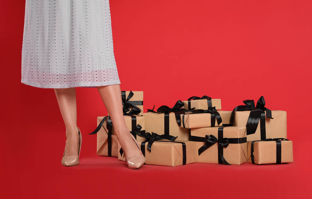 Woman and gift boxes on red background, closeup. Black Friday - Photo, Image