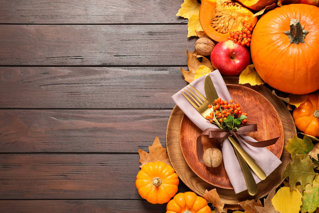 Flache Liegekomposition mit Tischdekoration, Gemüse und Herbstblättern auf hölzernem Hintergrund, Platz für Text. Erntedankfest - Foto, Bild