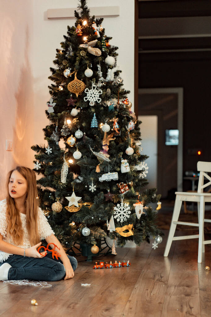 クリスマスツリーを背景に10代の女の子。クリスマス休暇だ。メリークリスマスとハッピーニューイヤーのコンセプト. - 写真・画像