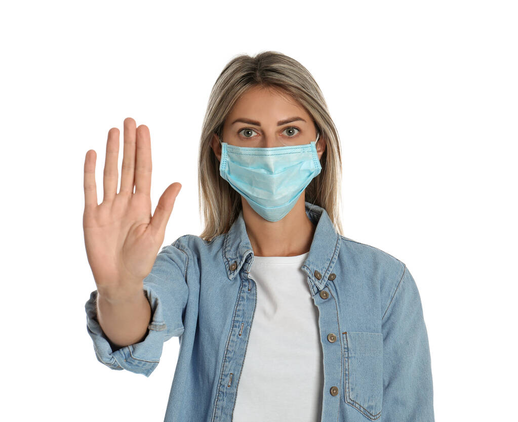Жінка в захисній масці показує стоп- жест на білому тлі. Запобігання поширенню коронавірусу
 - Фото, зображення