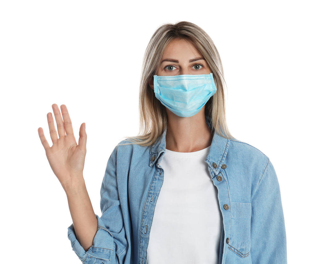 Mujer con máscara protectora mostrando un gesto de saludo sobre fondo blanco. Mantener la distancia social durante la pandemia de coronavirus - Foto, imagen