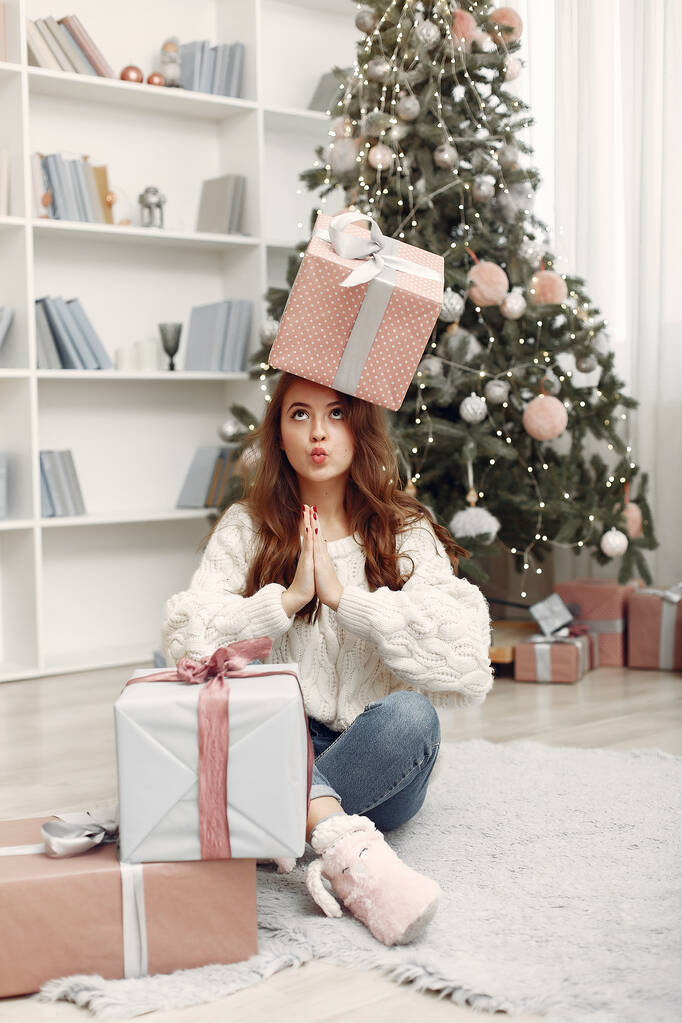 Девушка с рождественскими подарками в украшенной комнате - Фото, изображение