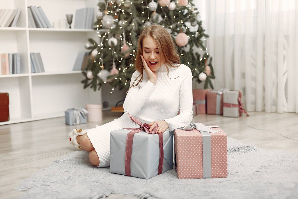Девушка с рождественскими подарками в украшенной комнате - Фото, изображение