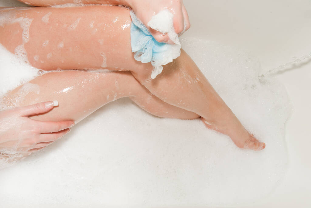 Mädchen wäscht Beine mit Schaum im Badezimmer - Foto, Bild