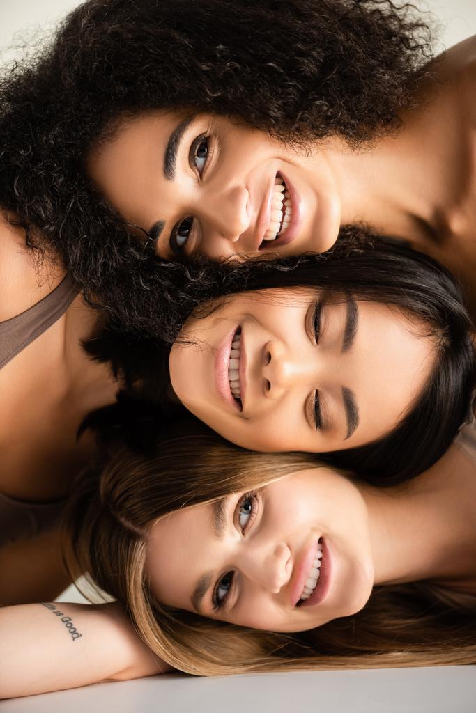 shora pohled na šťastné multikulturní modely při pohledu na kameru izolovanou na bílém  - Fotografie, Obrázek