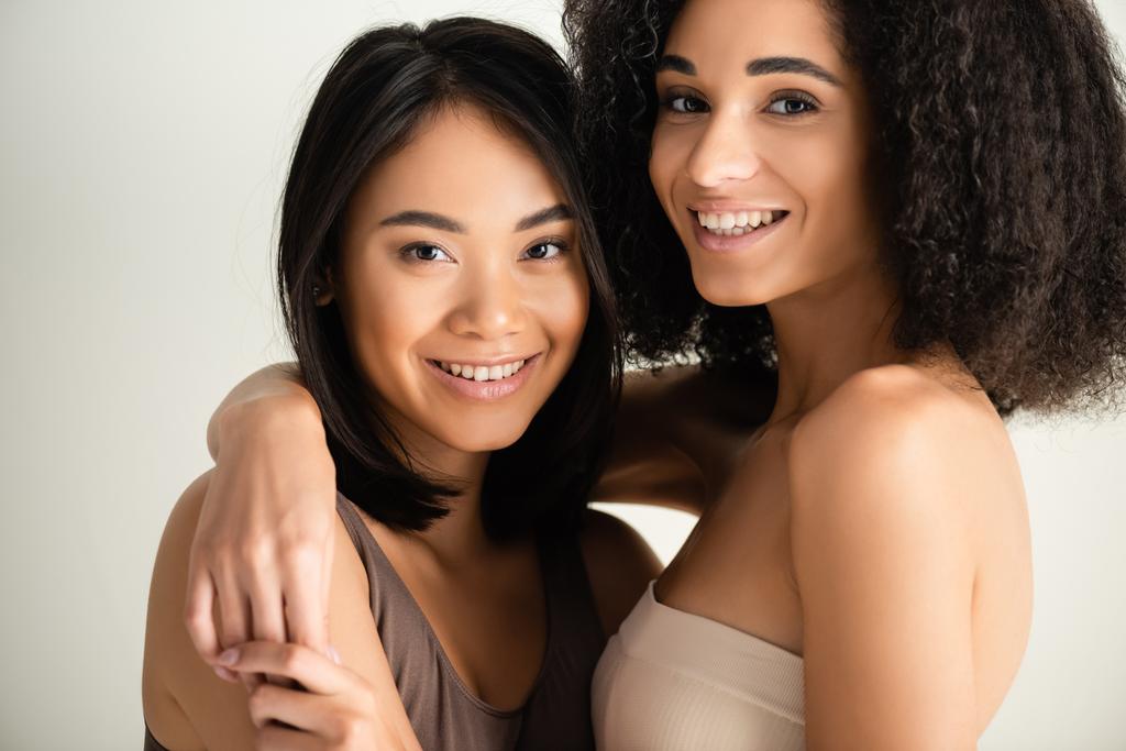 mosolygó afro-amerikai és ázsiai nők néz kamera elszigetelt fehér - Fotó, kép