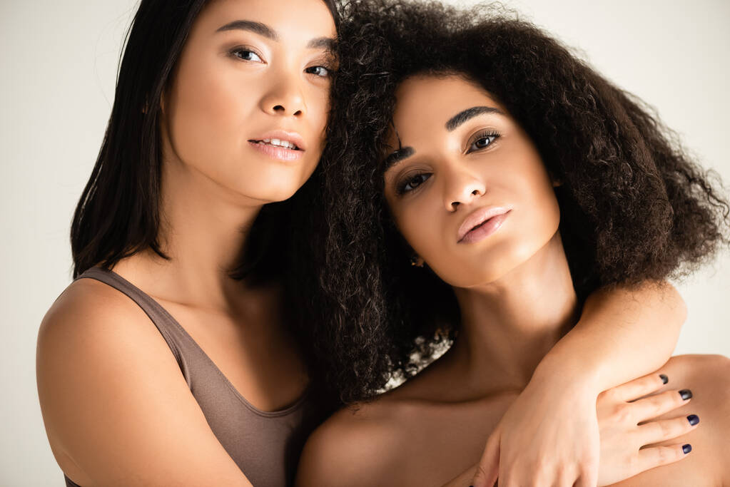 junge afrikanisch-amerikanische und asiatische Frauen umarmen sich isoliert auf weiß - Foto, Bild