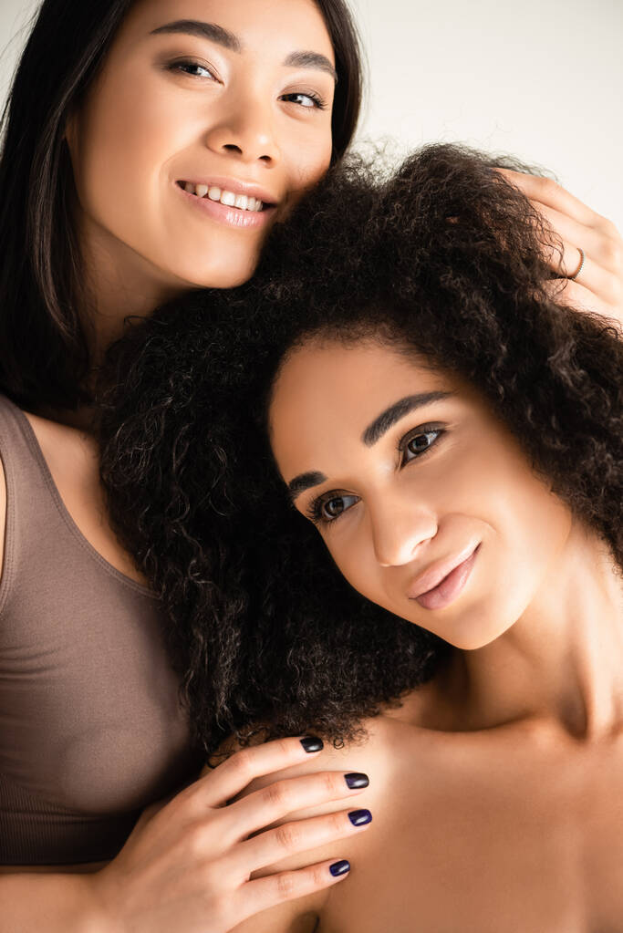 glücklich afrikanisch-amerikanische und asiatische Frauen umarmen sich isoliert auf weiß - Foto, Bild