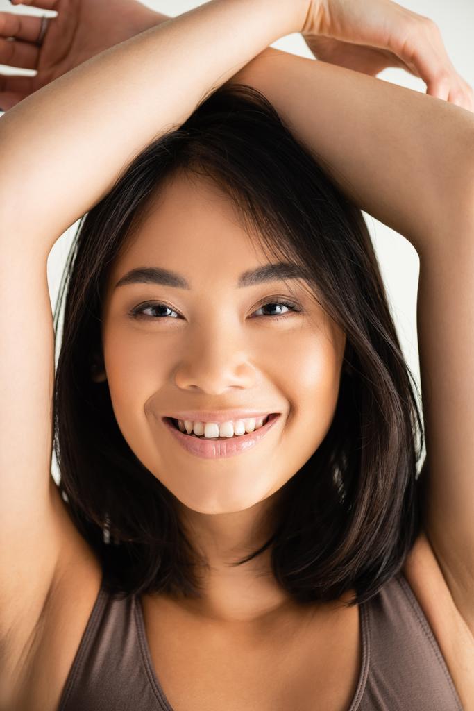 щаслива азіатська жінка з руками над головою сміється ізольовано на білому
 - Фото, зображення