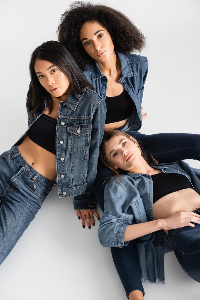 high angle view of trendy interracial women in denim outfit posing on white - Photo, Image