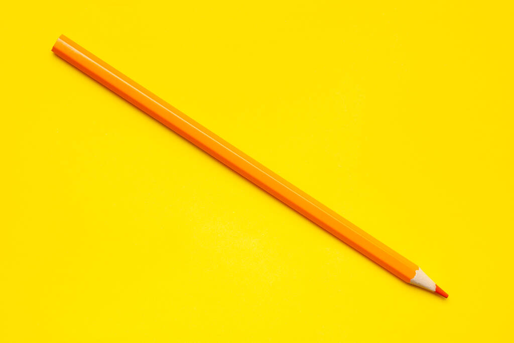 diagonalny pomarańczowy ostry drewniany ołówek na jasnożółtym tle, odizolowany, przestrzeń kopiowania, makieta - Zdjęcie, obraz