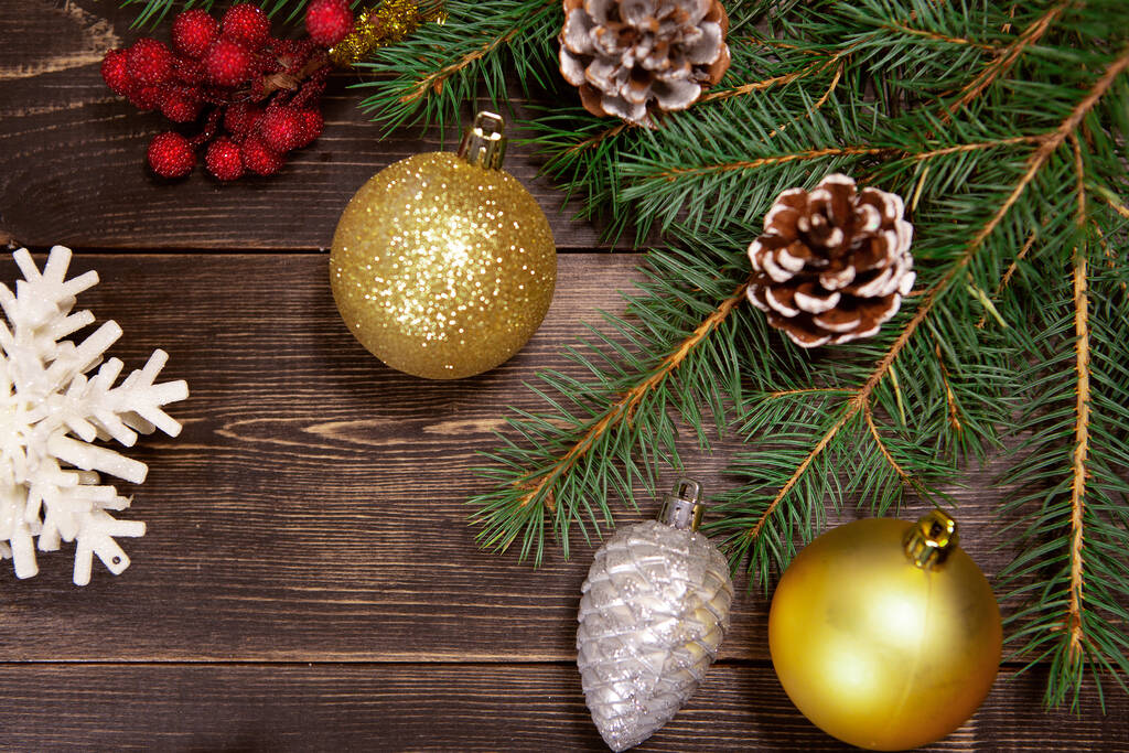 茶色の木製の背景にお祝いのモミの針を持つクリスマスのおもちゃ。テキストのための空のスペースを持つ新年の背景 - 写真・画像