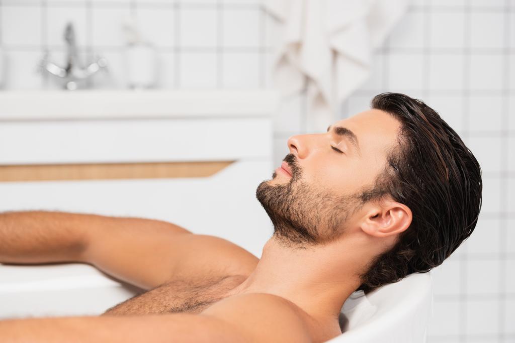 髭を生やした男が家で目を閉じてお風呂に入る  - 写真・画像
