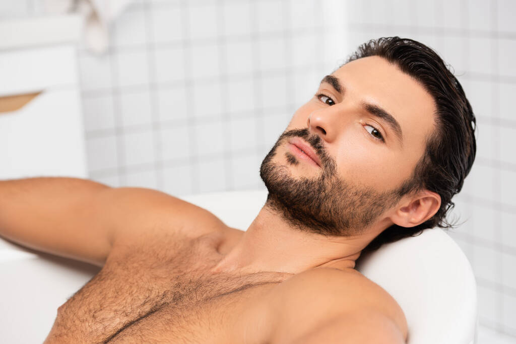 Бородатий чоловік дивиться на камеру, приймаючи ванну
  - Фото, зображення