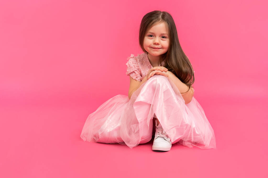 Kleines Mädchen, Studioporträt eines schönen Kindes in rosa Kleid auf rosa Hintergrund. - Foto, Bild