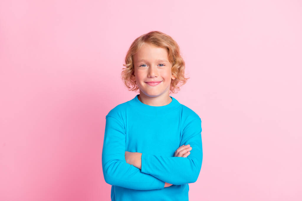 Фото маленького хлопчика зі складеними руками самодостатньо виглядає камера одягнена в синій черепаха ізольований пастельно-рожевий кольоровий фон
 - Фото, зображення