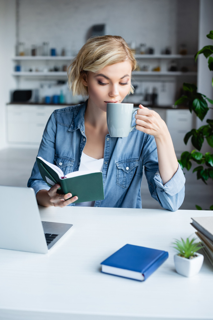 young blonde woman working from home and drinking tea - Photo, Image