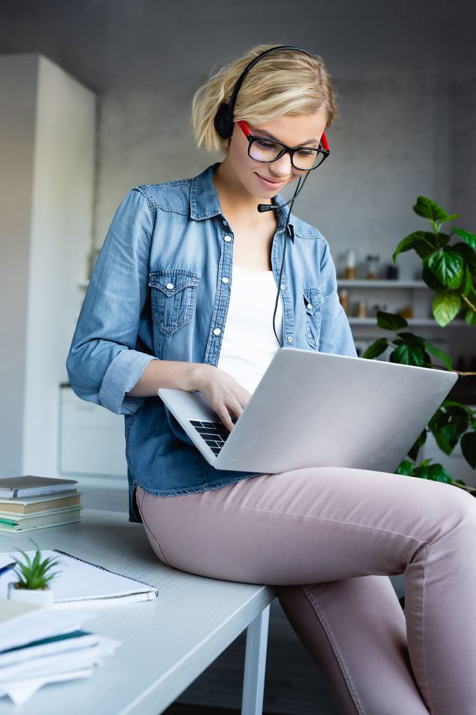 jong blond vrouw in bril typen op laptop - Foto, afbeelding