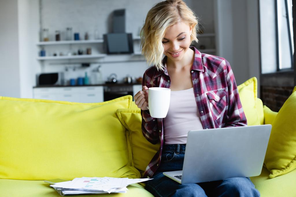 blondi nainen ruudullinen paita työskentelee kotoa ja juo teetä - Valokuva, kuva