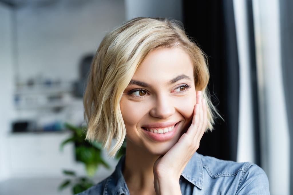 portrait of smiling blonde woman looking out window - Photo, Image