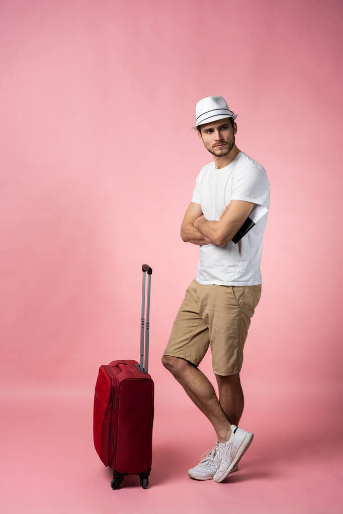 Ταξιδιώτης άνθρωπος με βαλίτσα, διαβατήριο και εισιτήριο στο φόντο χρώμα. - Φωτογραφία, εικόνα