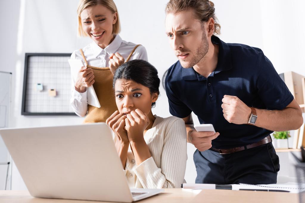Multikulturelle nervöse Büroangestellte schauen am Arbeitsplatz im Büro auf den Laptop - Foto, Bild