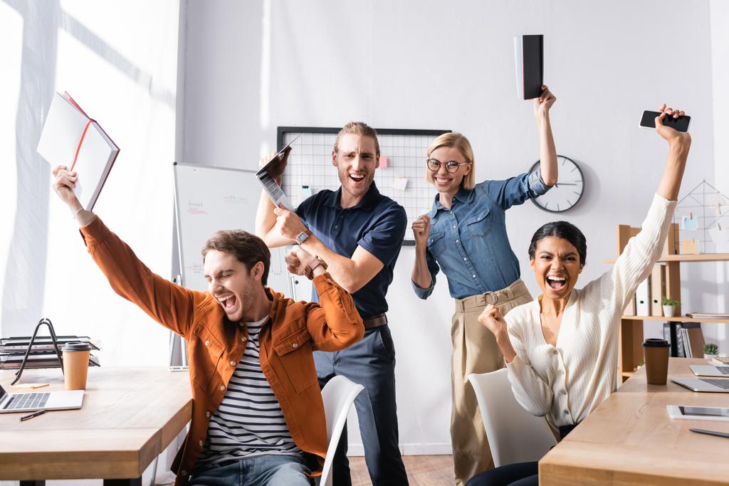 izgatott multikulturális üzletemberek kiabálnak és sikeres gesztust mutatnak az irodában - Fotó, kép