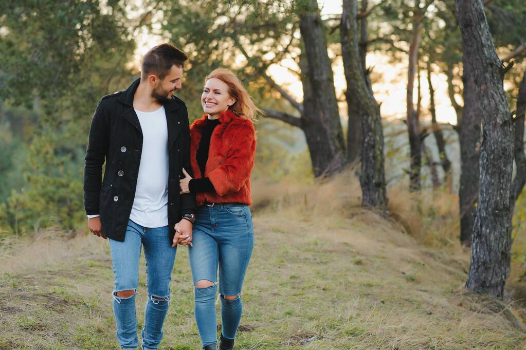 Nuori pari rakastunut kävely syksyllä puistossa kädestä katsoen auringonlaskuun - Valokuva, kuva