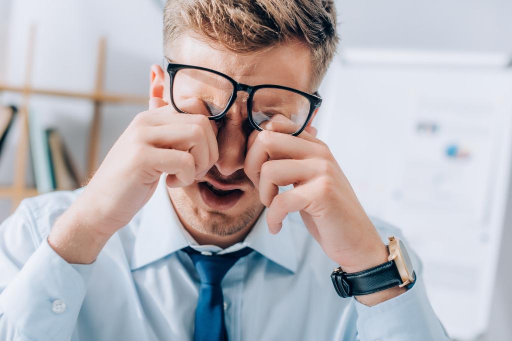 Виснажений бізнесмен розтирає очі під час роботи в офісі
 - Фото, зображення