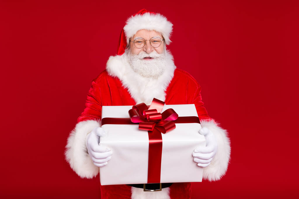 Portret van hem hij mooi knap aantrekkelijk vrolijk overgewicht blij bebaarde Santa vader in handen grote grote witte geschenkdoos vieren geïsoleerde helder levendige glans levendige rode kleur achtergrond - Foto, afbeelding