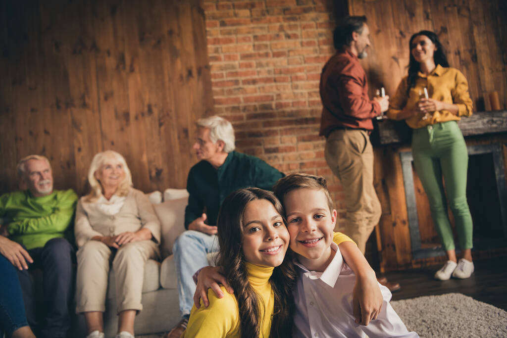 Foto de familia completa siete personas que reúnen a dos niños pequeños abrazan a los abuelos comunican que los padres beben vino espumoso sentado sofá generación en casa sala de estar por la noche en interiores - Foto, imagen