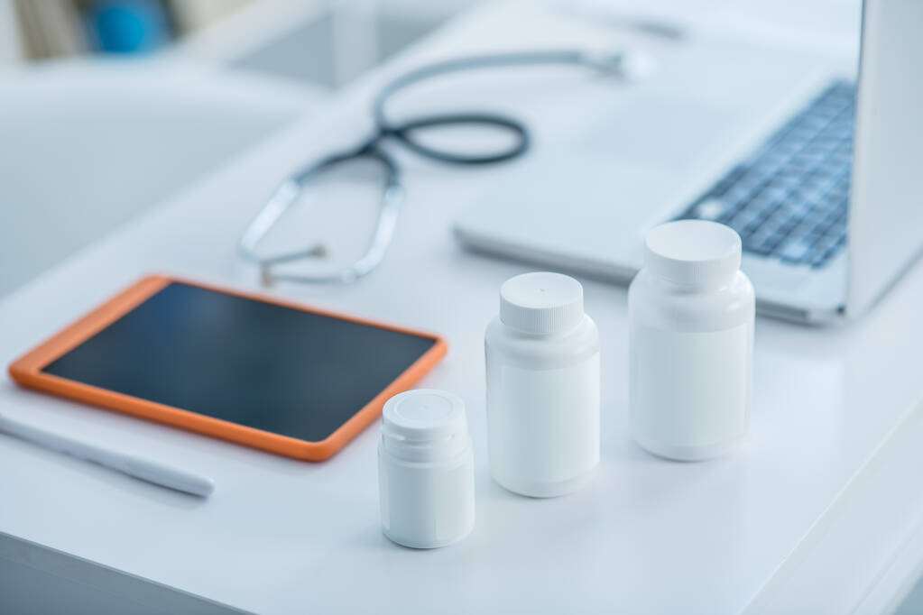 Fehér tartály gyógyszerrel és egy tabletta az asztalon - Fotó, kép