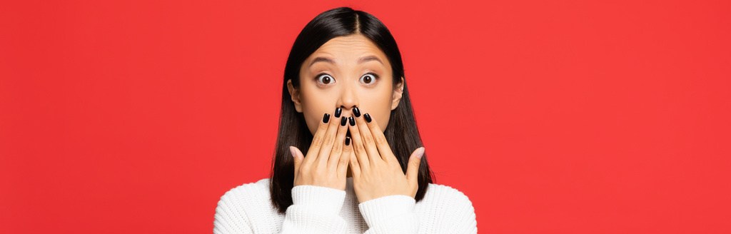 šokované asijské žena zakrývající ústa s rukama izolované na červené, prapor - Fotografie, Obrázek
