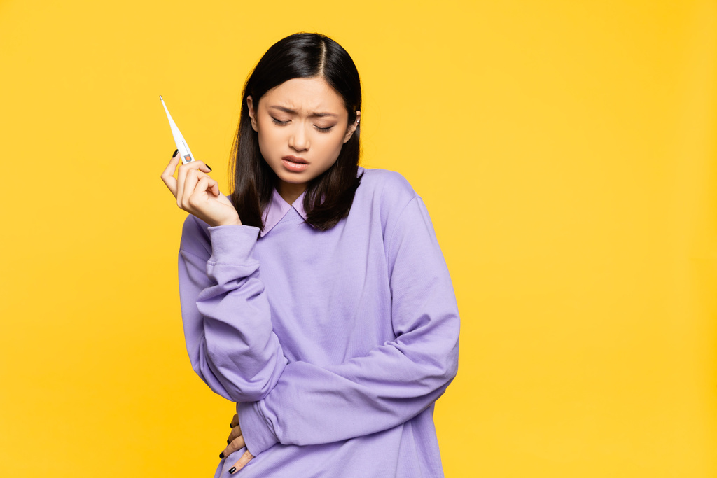 malade asiatique femme tenant numérique thermomètre isolé sur jaune  - Photo, image
