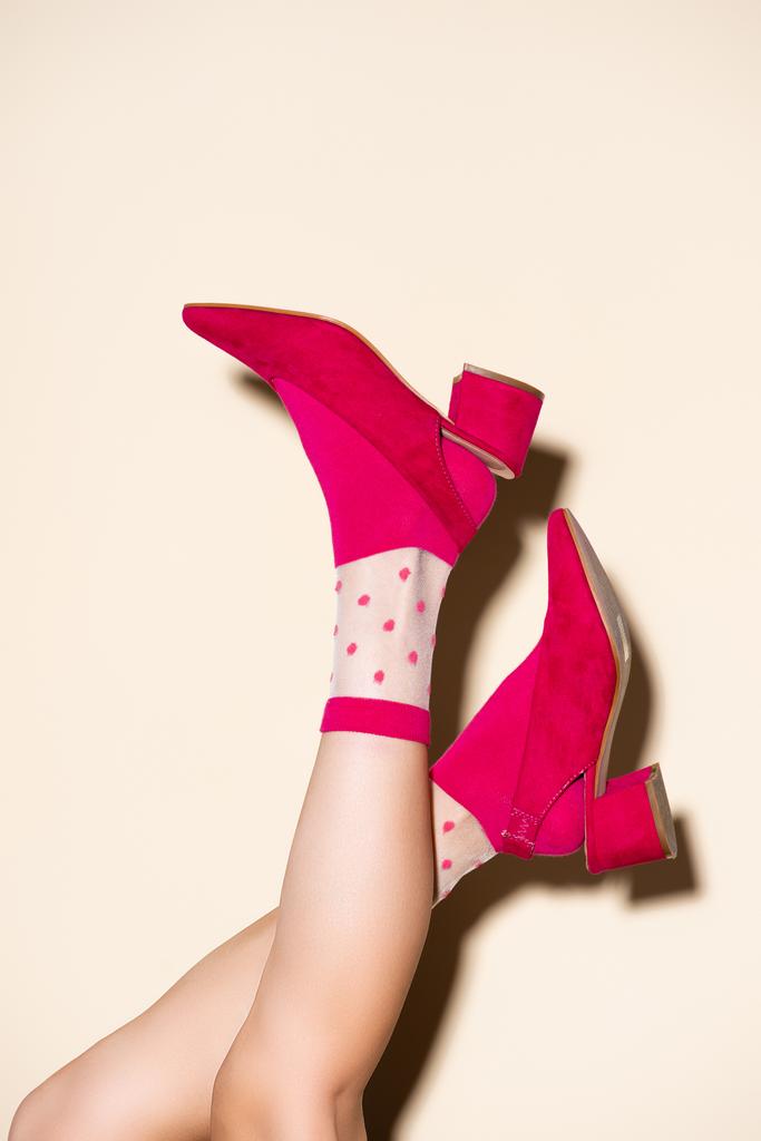 Ausgeschnittene Ansicht weiblicher Beine in rosa Retro-Socken und Schuhen auf beigem Hintergrund - Foto, Bild