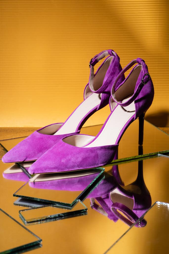 élégantes chaussures à talons en daim violet sur miroir sur fond jaune - Photo, image