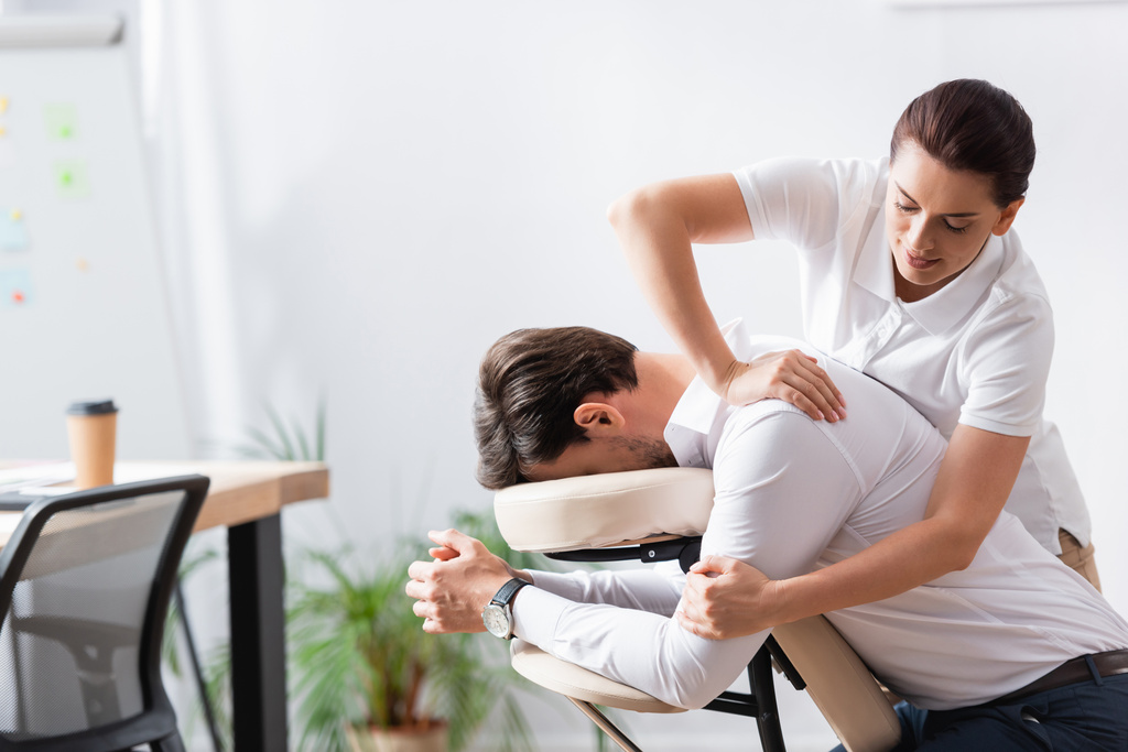 Позитивний масажист робить масаж рук для бізнесмена на розмитому фоні
 - Фото, зображення