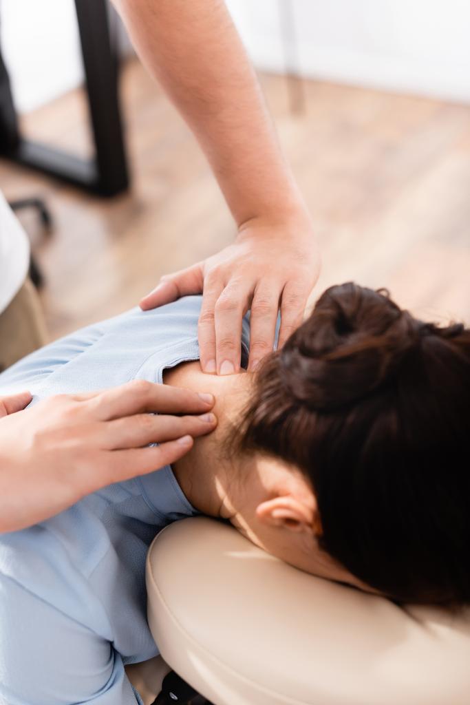 Крупный план массажера, делающего массаж шеи для бизнесвумен на размытом фоне - Фото, изображение