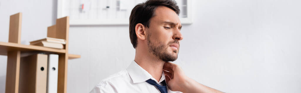 Businessman holding hand on aching neck, while looking away in office, banner - Photo, Image