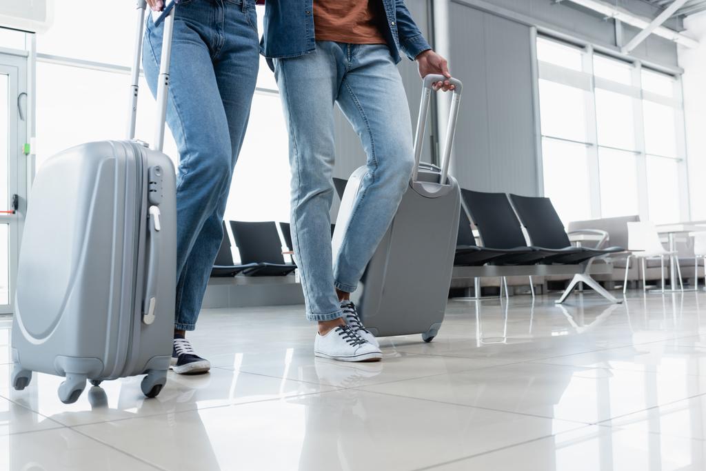 частичный вид на пару, идущую с багажом в аэропорту  - Фото, изображение
